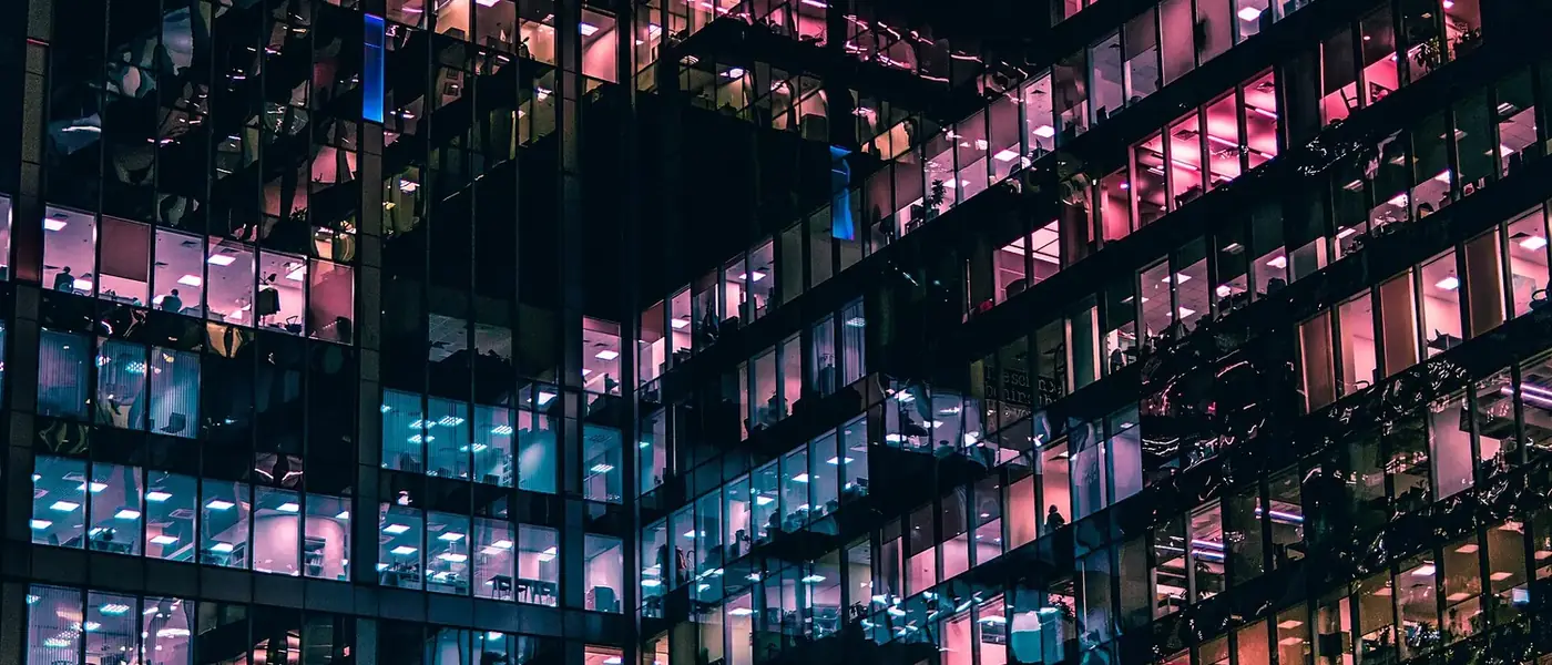 Dozens of lit office windows across the face of a building at night