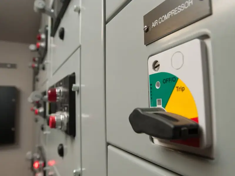 A switchgear cabinet handle set against a green, yellow and red position dial